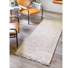 a white rug on the floor next to two chairs and a plant in a pot