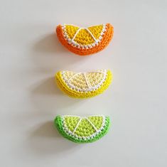 three pieces of crocheted fruit sitting on top of a white table next to each other