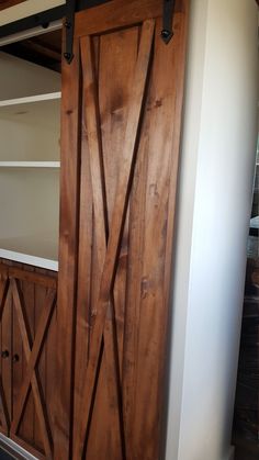 an open wooden door in the corner of a room next to a shelf with shelves