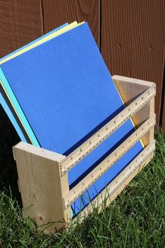 a wooden box filled with blue folders sitting in the grass