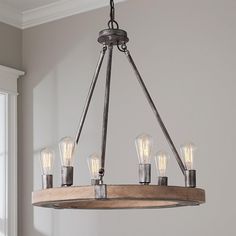 a wooden chandelier with six lights hanging from it's center beam in a living room