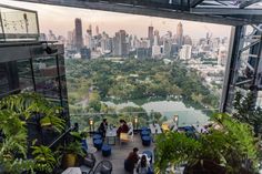 people are sitting at tables on top of a high rise overlooking the cityscape