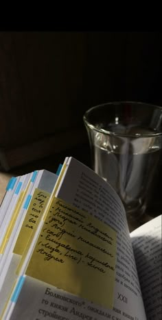 an open book sitting on top of a table next to a glass filled with water