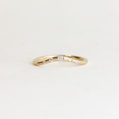 a yellow gold ring with three diamonds on the top and bottom, sitting on a white surface