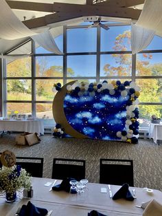 a room with tables and chairs set up in front of large windows that look out onto the sky