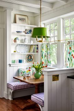 a kitchen table with two chairs and a green lamp hanging from the ceiling above it