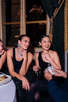 three women are sitting at a table and one woman is holding a piece of cake