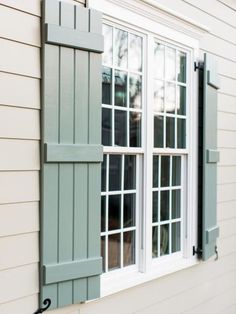 an open window with green shutters on the side of a house