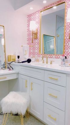 a bathroom with pink and white wallpaper, gold trimmings and an ottoman