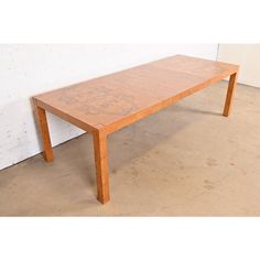 a wooden table sitting on top of a floor next to a white wall and cement floor