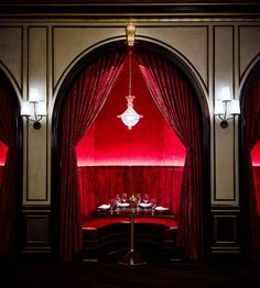 a room with red velvet curtains and chandelier hanging from it's ceiling