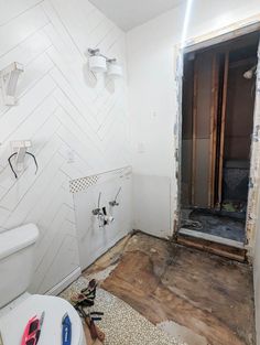 a bathroom that is being remodeled with wood flooring and white wall tiles on the walls