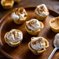 small desserts are arranged on a wooden plate with a spoon next to them,