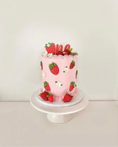 a pink cake with strawberries on top and the word love spelled in cursive writing