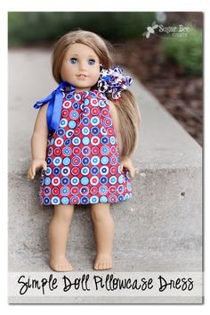 a doll with blonde hair wearing a blue and red polka dot dress, standing on concrete