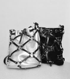 Sin caged bucket bag is a drawstring crossbody/shoulder and handbag by MadElephant. The garment is made of genuine black/silver leather and premium quality metal details. Black caged bucket bag is designed with leather stripes and rings. It has a black lining fabric and a zipper pocket inside. Closure - drawstring and magnet. A handle is detachable. There is an adjustable shoulder strap detailed with chains (86-110 cm/33.8-43.3 inch.). Both straps have carabiners. Silver and black colors Dimensions: -Height 30 cm/11.8 inch. -Depth 15 cm /5.9 inch. -Width 28 cm/11 inch. Purses And Handbags Silver And Black, Luxury Streetwear Bag With Adjustable Strap, Luxury Contemporary Bags With Detachable Strap, Cheap Gothic Bags With Adjustable Strap, Luxury Edgy Bags With Metal Hardware, Luxury Edgy Bag With Metal Hardware, Harness Bag, Cage Bag, Black Waist Belt