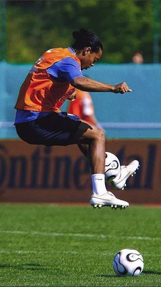 a man kicking a soccer ball on top of a field