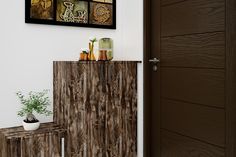 a wooden cabinet sitting next to a plant on top of a table in front of a door