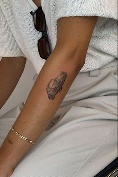 a woman's arm with a tattoo on her left wrist and sunglasses on the other hand