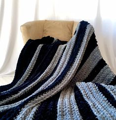 a blue and white crocheted blanket sitting on top of a chair