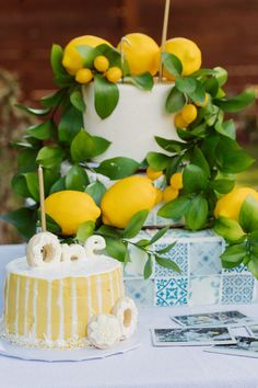 a cake sitting on top of a table covered in lemons and greenery next to a card board