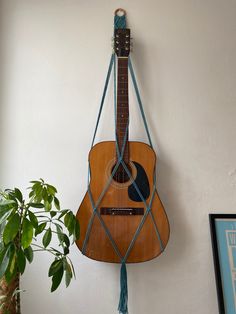 a guitar hanging on the wall next to a potted plant