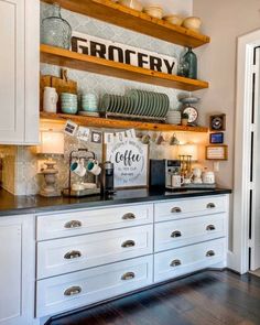 a kitchen with white cabinets and black counter tops, open shelving above the stove