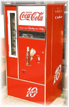 an old fashioned coca cola machine sitting on the ground