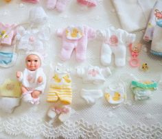 there are many baby items laid out on the table together, including clothes and dolls