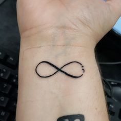 a wrist tattoo with an infinite symbol on it