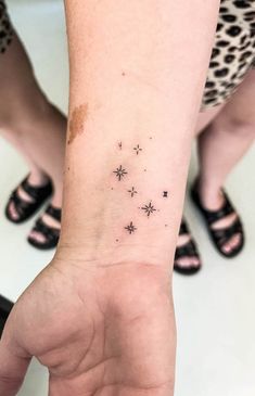 a woman's wrist with small stars tattooed on the left side of her arm