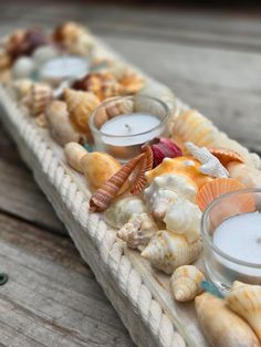 several candles are placed on a tray filled with seashells