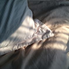 an unmade bed with two pillows on top of it and the sheets pulled back