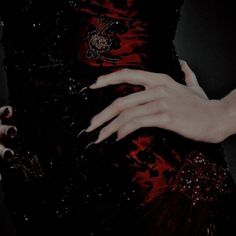 a woman's hand with black and red nail polish on her nails holding onto the dress