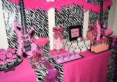 a pink and black party with zebra print decorations on the walls, table cloths and cake