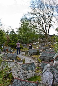 a woman is standing in the middle of a miniature village with lots of houses and trees