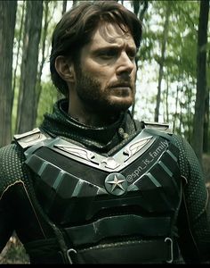 a man in armor standing in the woods