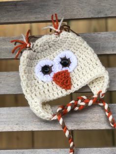 a crocheted hat with an orange nose and eyes is sitting on a wooden bench