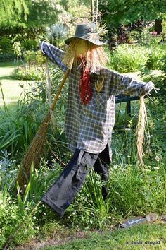 a scarecrow is standing in the grass with a broom