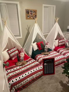 two beds in a room decorated for christmas with red and white bedding, pillows and blankets