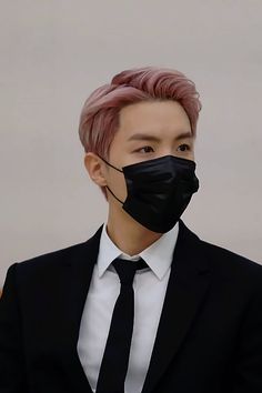 a man with pink hair wearing a black face mask