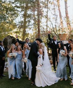 a bride and groom kissing in front of their wedding party