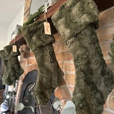 two stockings hanging from a fireplace with moss growing on them and the mantel in the background