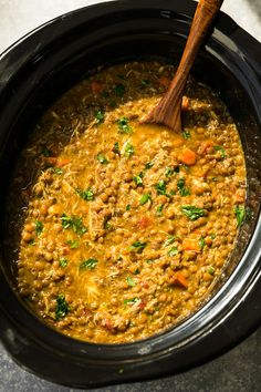 a wooden spoon in a slow cooker filled with food