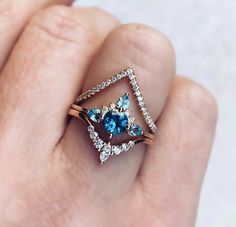 a woman's hand holding a diamond and blue topaz ring with diamonds on it