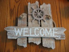 a wooden sign that says welcome with a ship wheel on the front and side of it