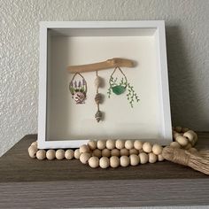 a shadow box with beads and wooden bead necklaces in it on a shelf