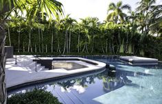 an outdoor swimming pool surrounded by trees and bushes, with lounge chairs on the side