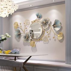 a dining room table with chairs and a round mirror on the wall above it is decorated with flowers