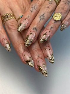 a woman's hands with gold nail polish and tattoos on their fingers, holding onto her nails